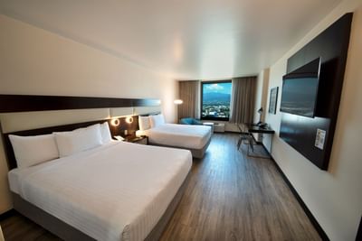Queen Bed Panoramic View with two bed, TV, chair by window and work desk at D Sabana Hotel, San Jose Costa Rica Hotel