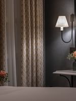 Elegant room interior with bed, curtains, and flowers at The Capital Hotel, Apartments & Townhouse