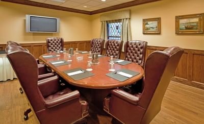 Starbird event room with a wooden conference table surrounded by leather chairs and wall TV at Clayton Plaza Hotel