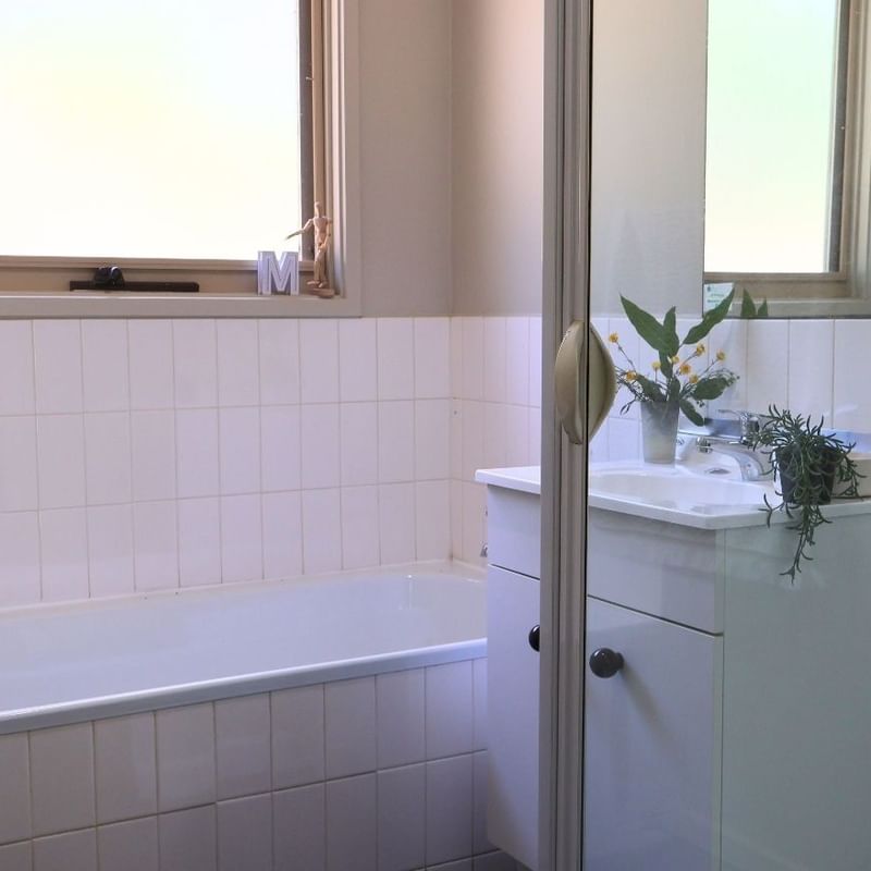 Clean bathroom with bathtub, sink, and window at La Trobe University - Villas.
