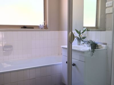 Clean bathroom with bathtub, sink, and window at La Trobe University - Villas.