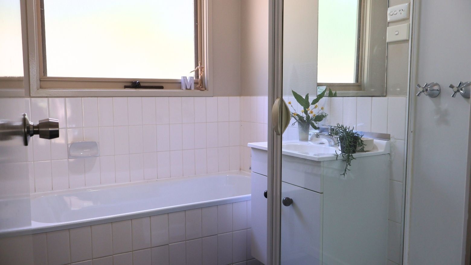 Clean bathroom with bathtub, sink, and window at La Trobe University - Villas.