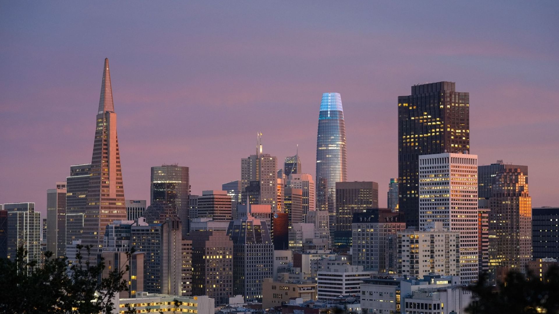 A city skyline at sunset with many skyscrapers