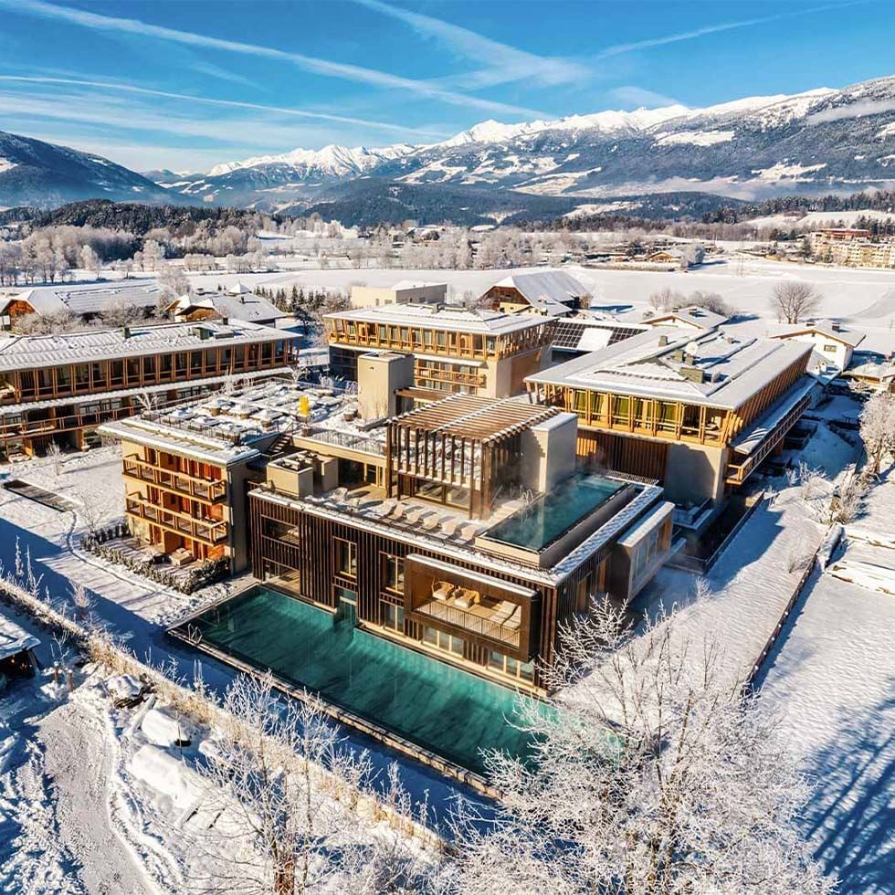 Aerial view of Falkensteiner Hotel Kronplatz surrounded by snow-covered mountains and trees