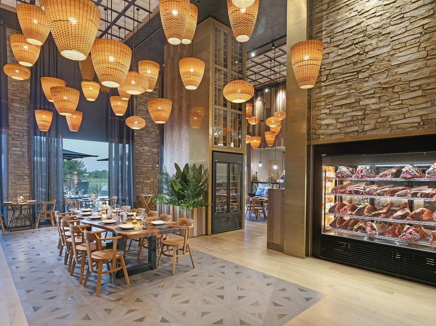 Dining area with hanging basket lamps and a meat display in Beef Grill Club at Cullinan Belek
