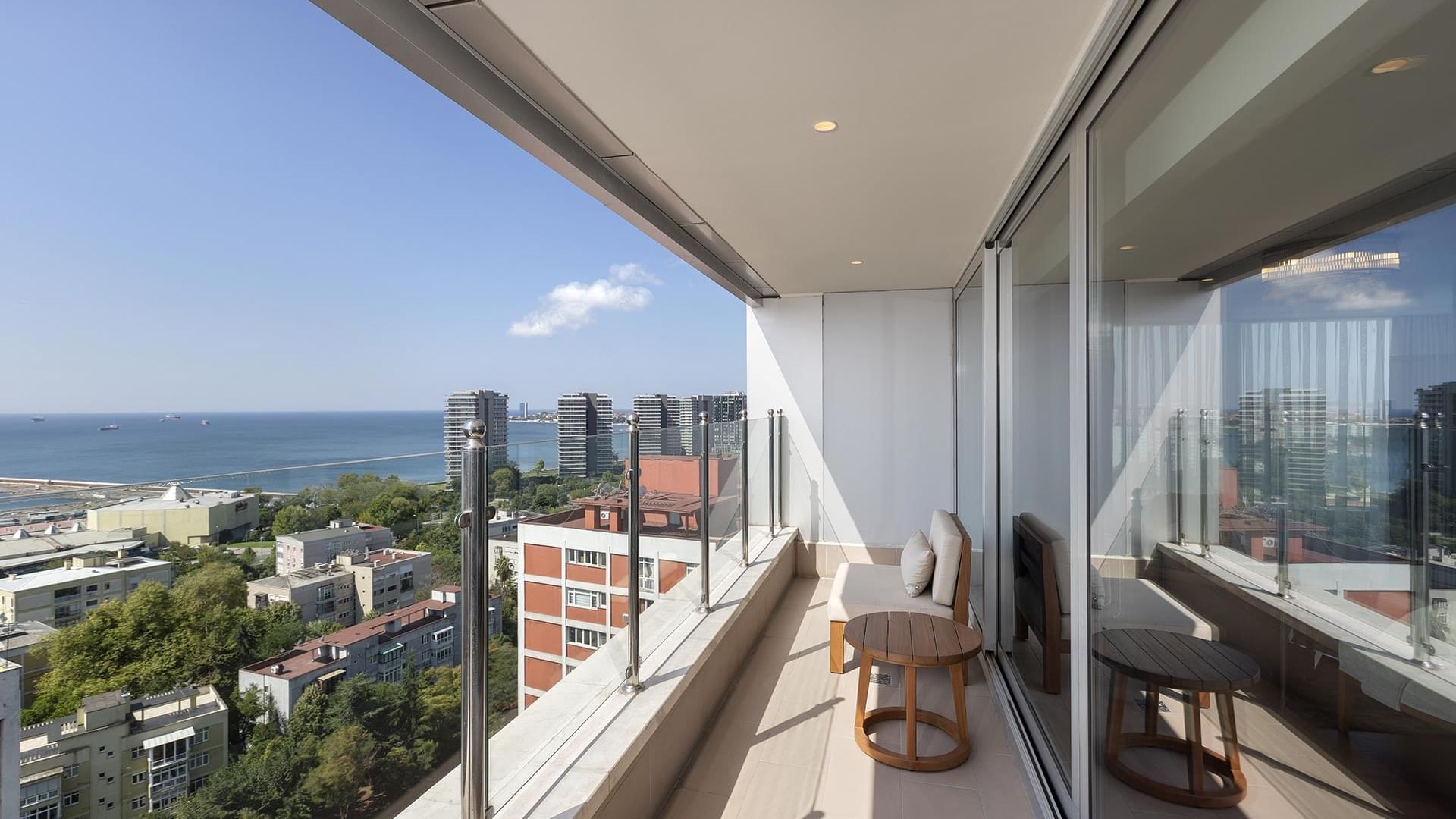 Titanic Port Bakırköy'de, cam korkuluklu, ahşap mobilyalı, şehir ve okyanus manzaralı Suite odada balkon.