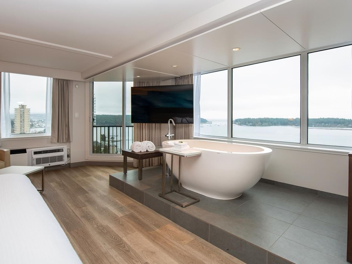 Spacious suite with a king bed, large windows, bathtub, and ocean view at Coast Bastion Hotel in Nanaimo.