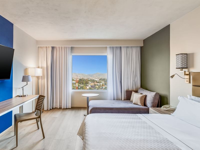 Prime Suite with double bed, seating area, workspace, and large window offering city and mountain views at Fiesta Inn