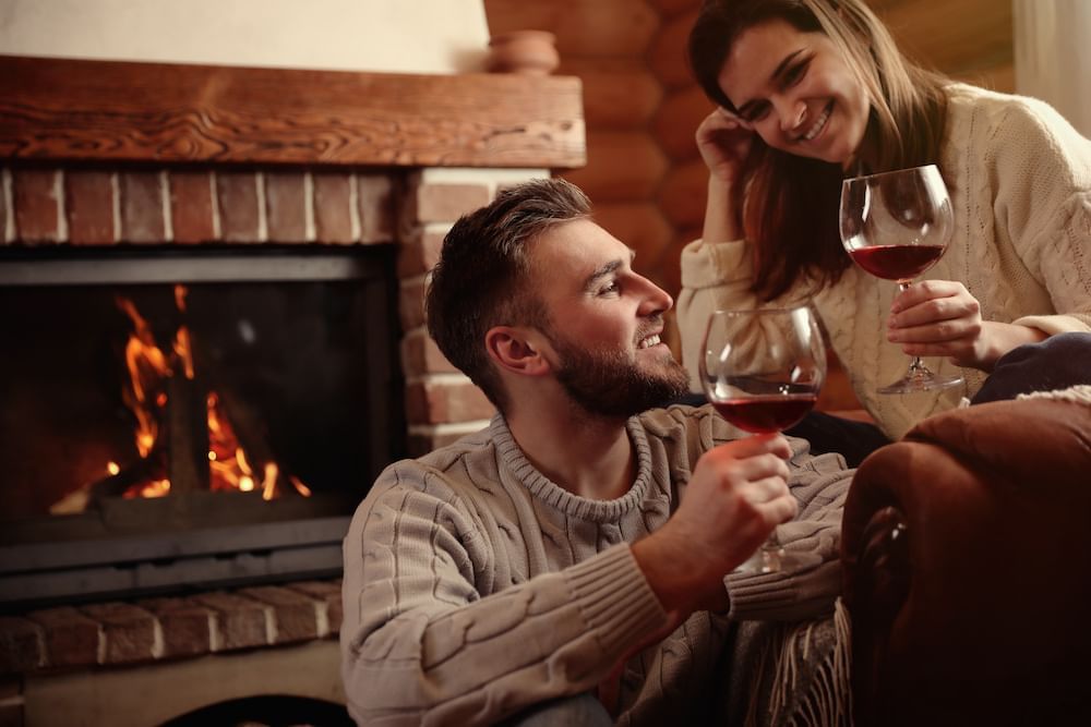 Happy couple enjoy wine by the cozy fire pit in a modern lounge area at Cove Pocono Resorts