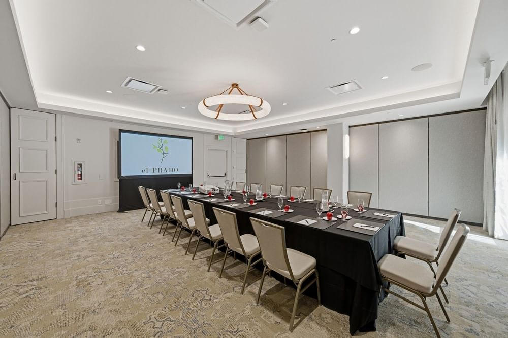 meeting room set up at el PRADO with a screen at the end of the table reading el PRADO with a yellow flower