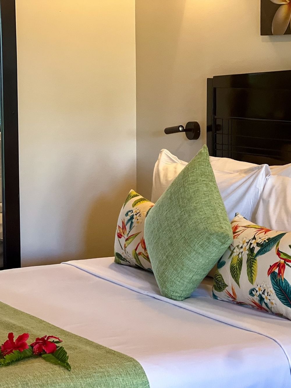 Elegantly decorated Deluxe Villa bedroom with tropical pillows and fresh flowers at Tokatoka Resort - Fiji International Airport, Nadi.