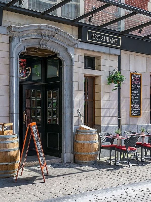 Chutney’s Restaurant's outdoor patio featuring chairs placed by tables under a glass canopy at Warwick Grand Place Brussels