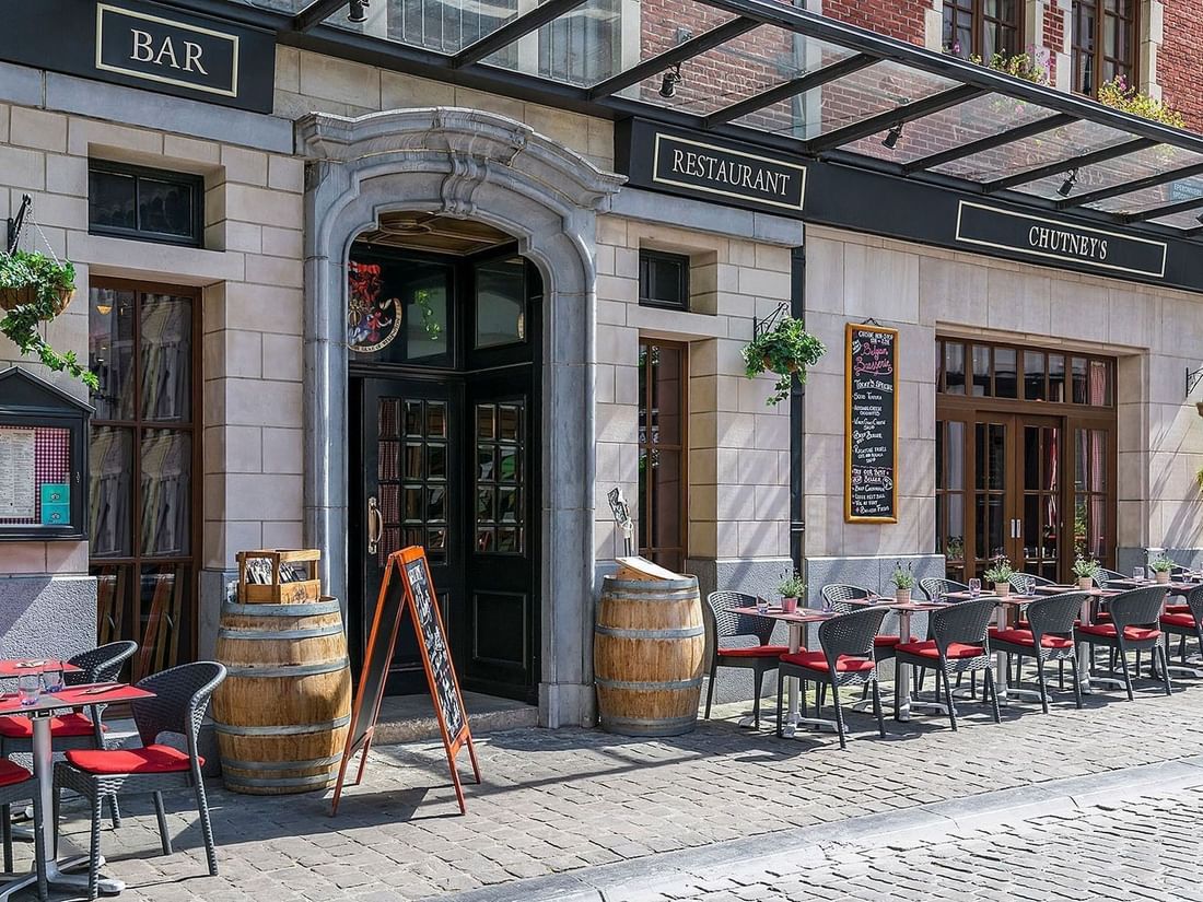 Chutney’s Restaurant's outdoor patio featuring chairs placed by tables under a glass canopy at Warwick Grand Place Brussels