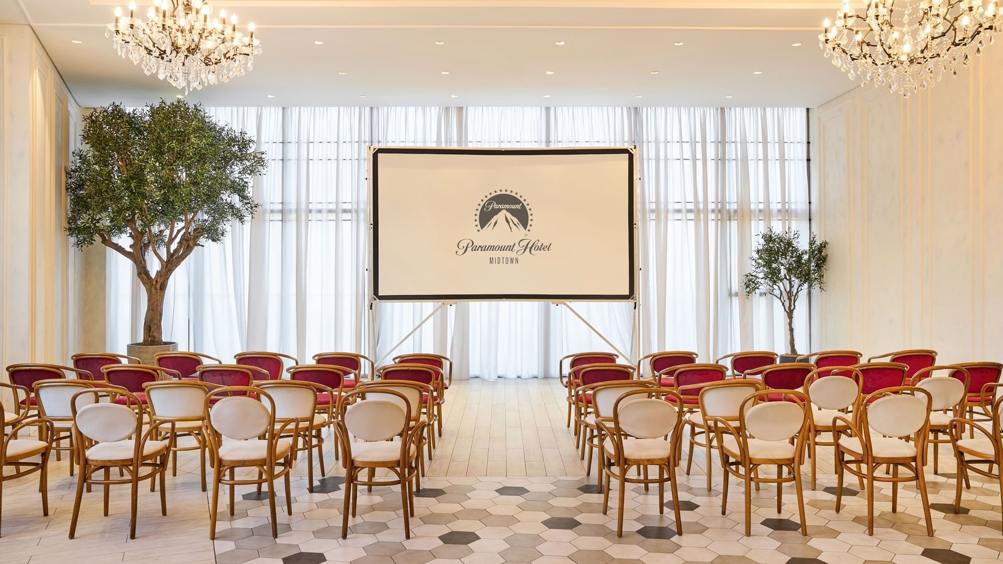 Auditorium-style seating arrangement facing a projector screen in Paparazzi restaurant venue at Paramount Hotel Midtown