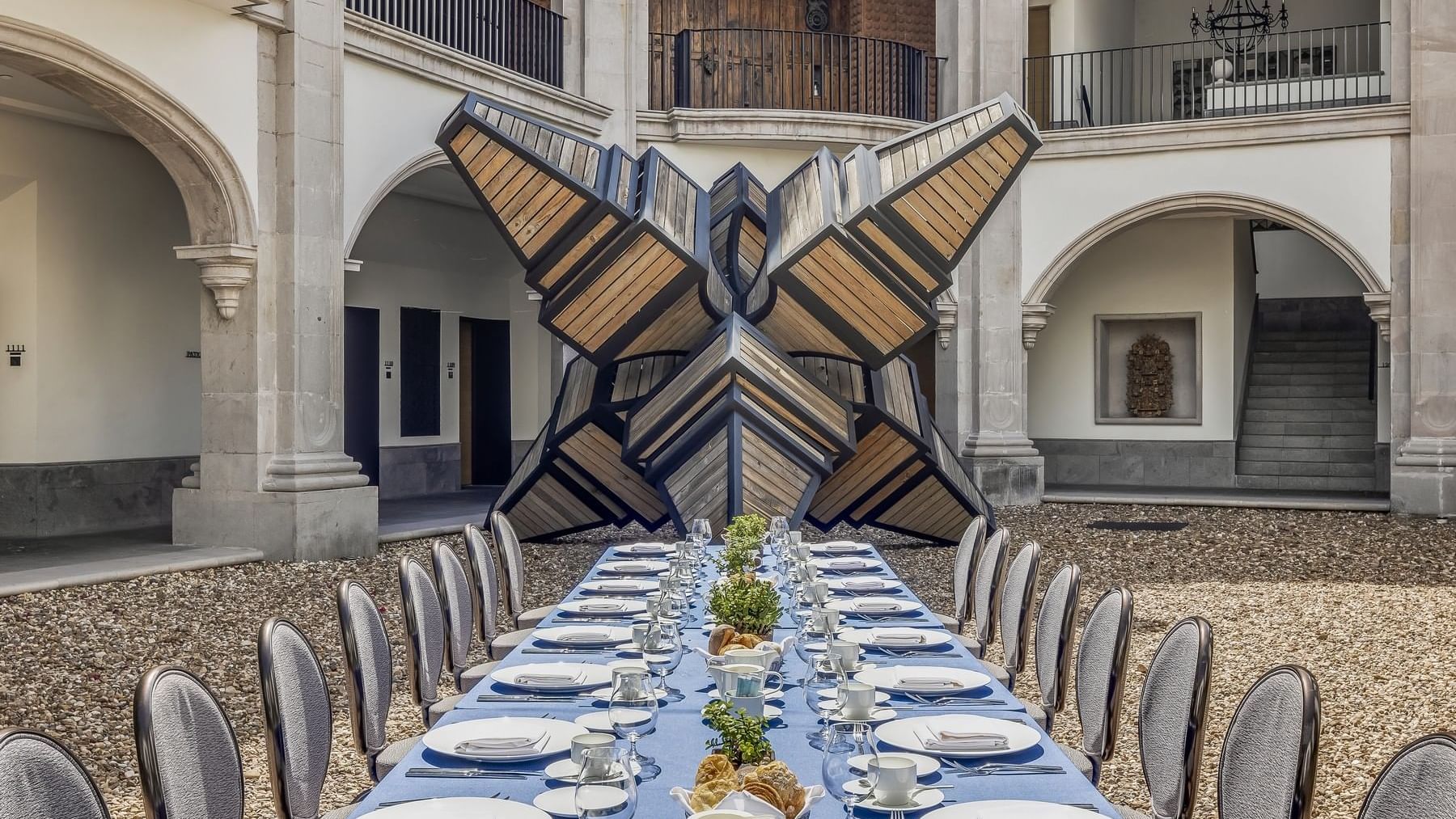 Dining table set-up in the courtyard next to a giant sculpture at Live Aqua San Miguel de Allende