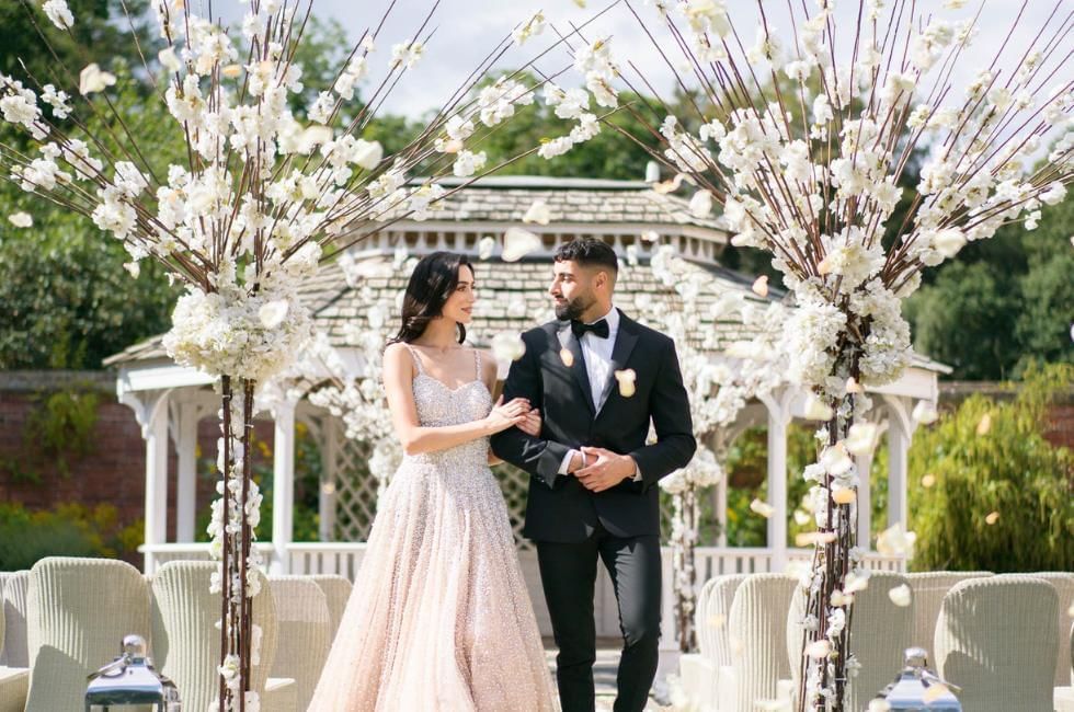 Asian wedding brochure image featuring couple walking from Mandap
