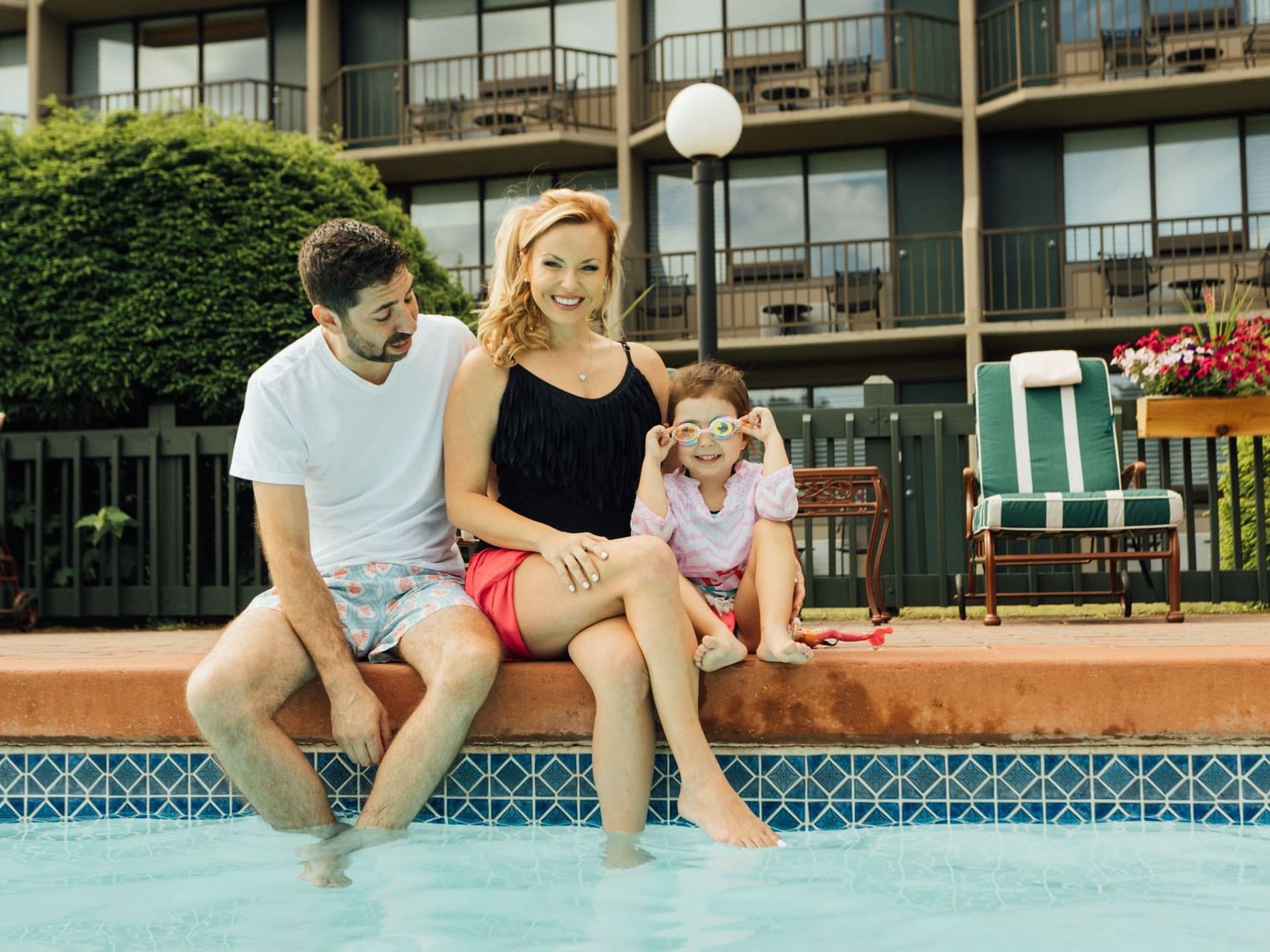 Family of three sitting on the poolside edge with their feet in the water at High Peaks Resort