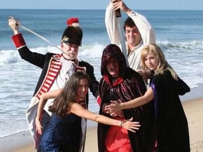 A group of people dressed in costume on the beach, posing playfully with props near Breezeway Boutique Hotel
