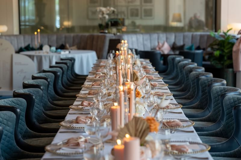 Elegant dining table setup with lit candles and plush chairs in Sofitel Brisbane Central