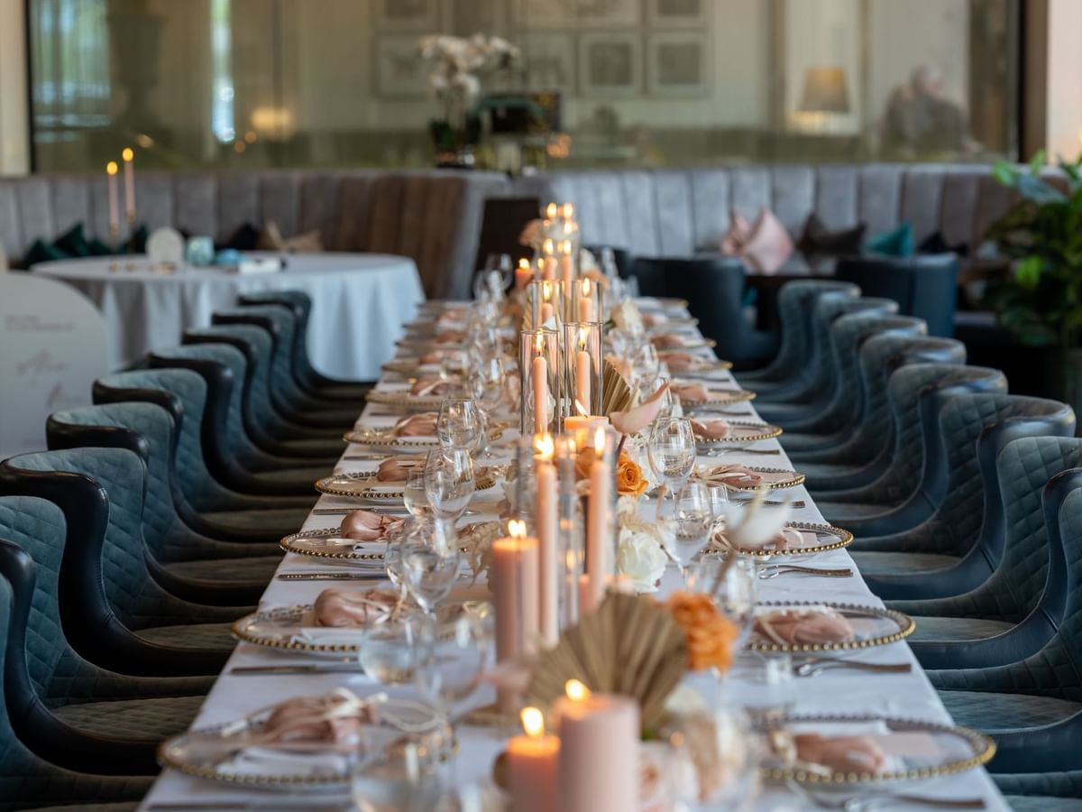 Dining table set with candles, flowers, and blue chairs in wedding event at Sofitel Brisbane Central