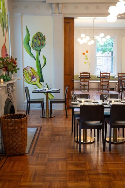 Elegant dining room with artichoke wall mural, parquet floors, and modern globe lighting at The Ashbrook Hotel