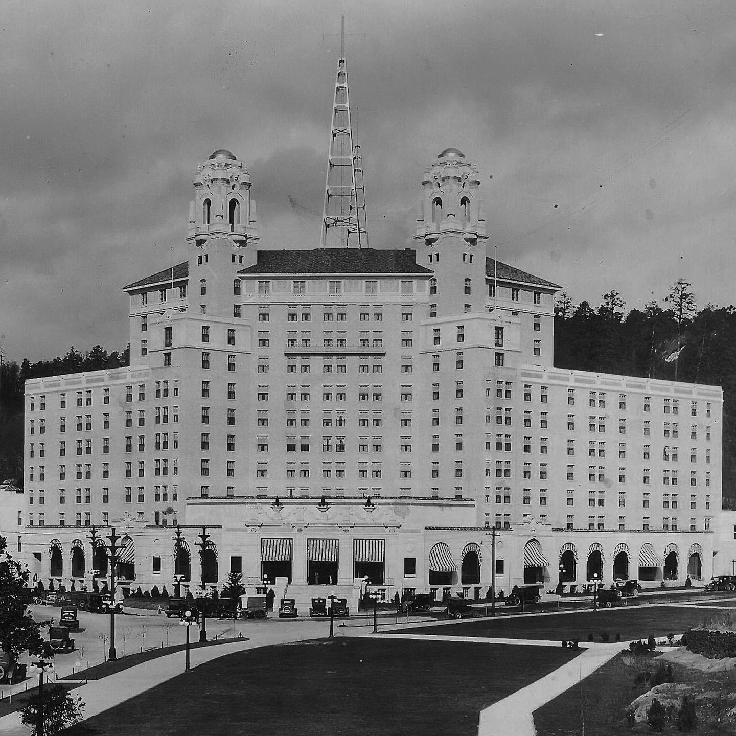 Black and white exterior of Arlington Resort Hotel & Spa with twin towers and vintage cars parked along the front entrance