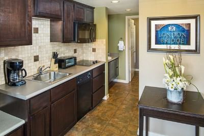 Fully equipped kitchen with dark wood cabinets, tile backsplash, and modern appliances at London Bridge Resort