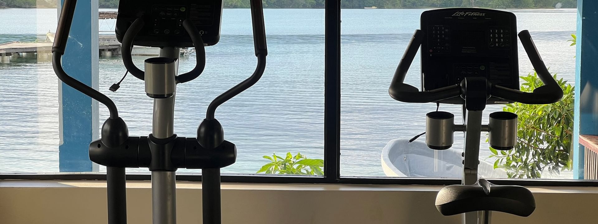 Two exercise bikes in a gym with a lake view at Warwick Le Lagon - Vanuatu in Efate