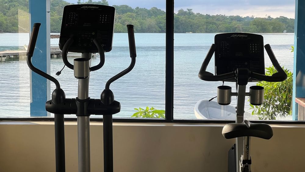 Two exercise bikes in a gym with a lake view at Warwick Le Lagon - Vanuatu in Efate.