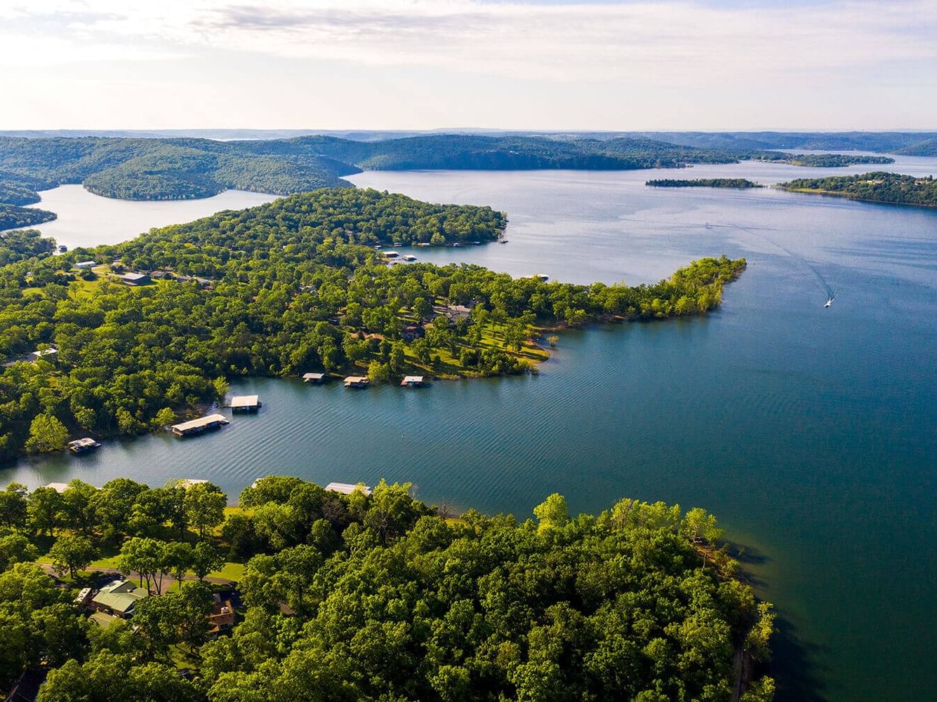 Aerial view of a lush green peninsula & private boat docks along a vast, winding Table Rock Lake near Branson Hillside Hotel
