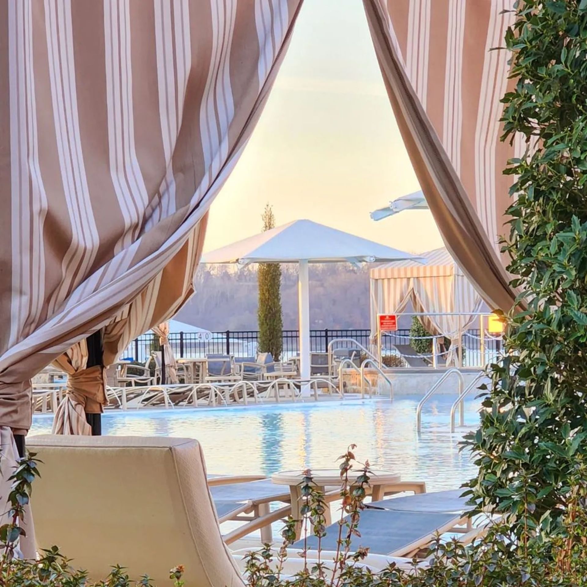 View of swimming pool through the opening of a striped cabana curtain at Shangri-La Resort and Golf Club