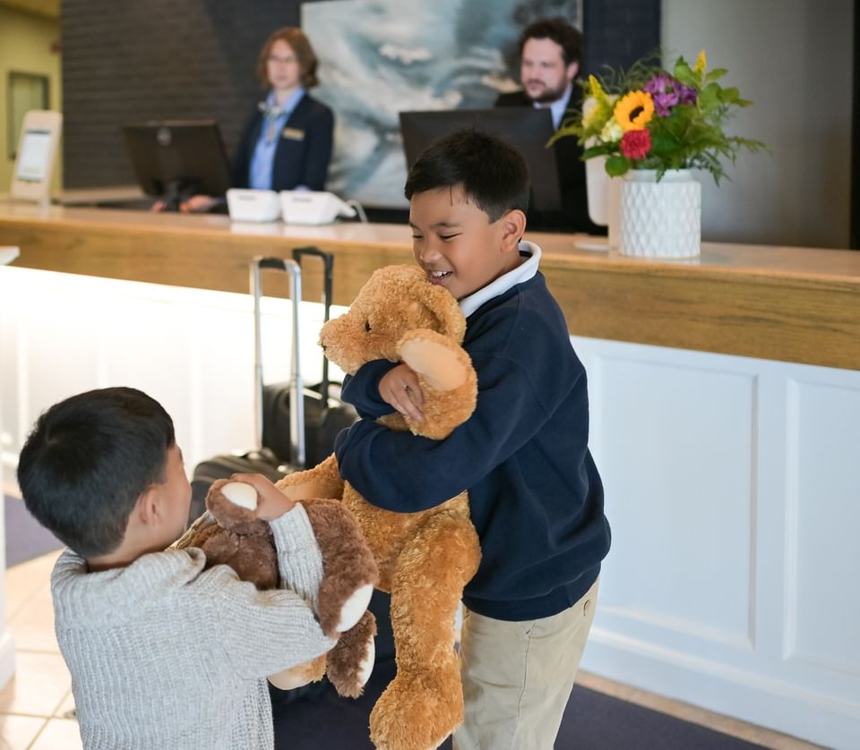 Two young boys holding teddy bears at the reception desk of Rodd Grand Yarmouth, a welcoming family hotel in Yarmouth