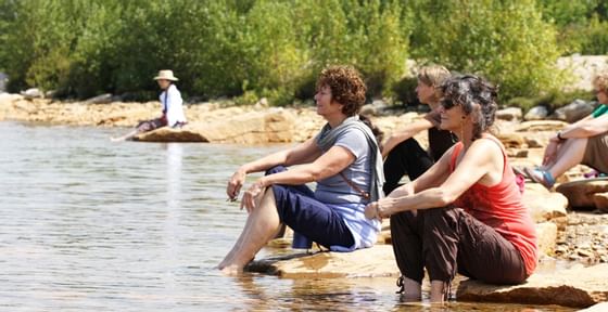 People sitting on rocks with feet in lake