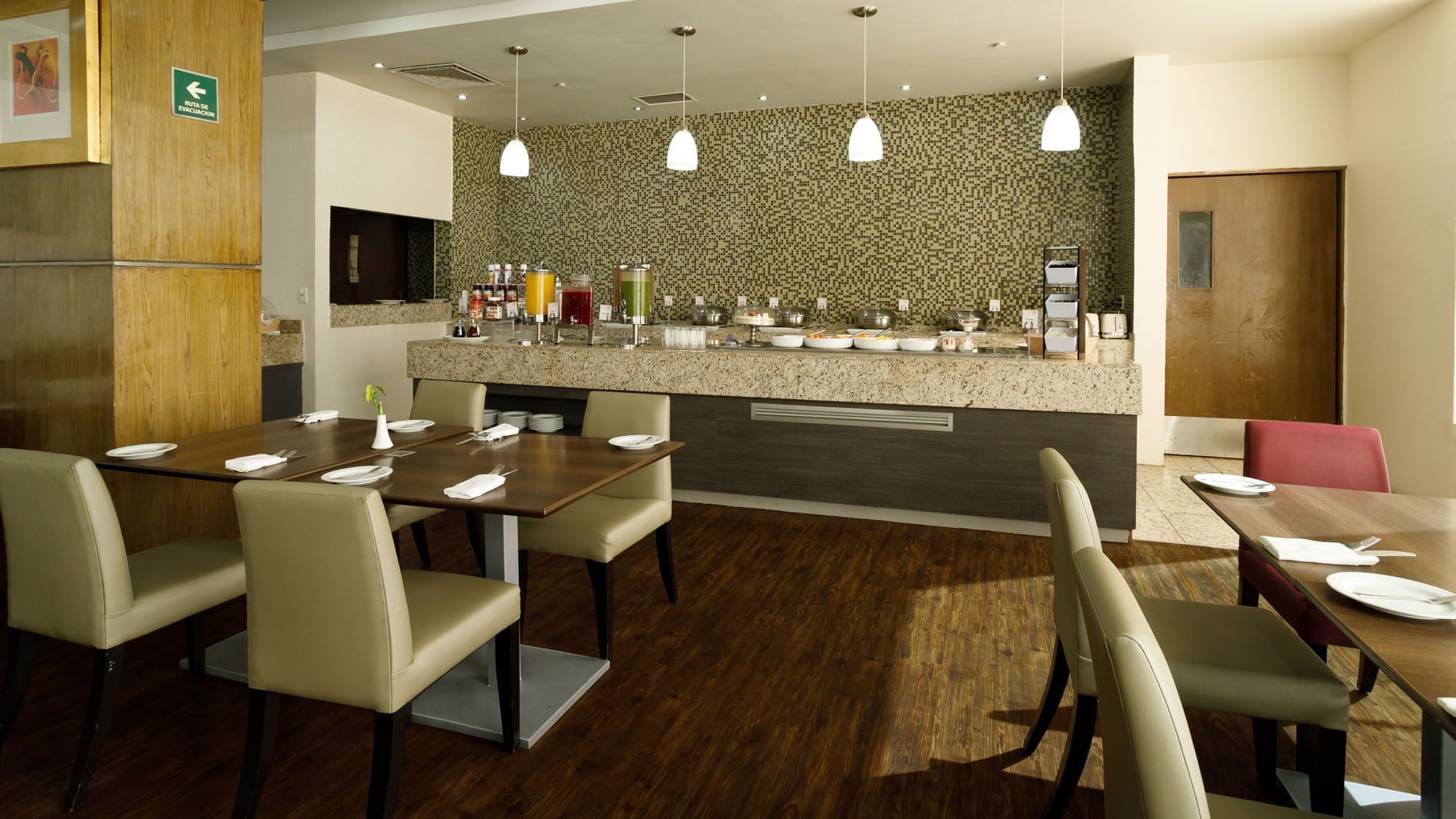 Modern breakfast buffet area in Stock Café featuring fresh juices and a clean, stone service counter at Real Inn Torreon
