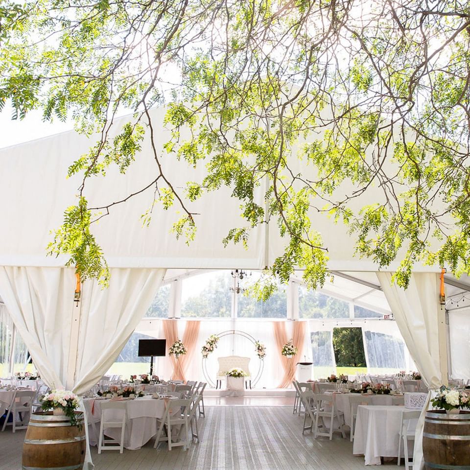 Spencer Meadows Pavilion decorated for dining and ceremony with a floral arch at Spencer Hotel & Conference Centre