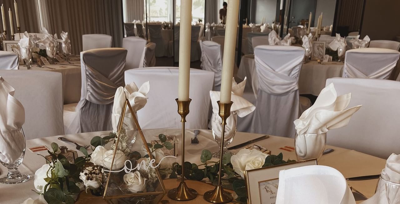 Table with candles, flowers, napkins, and glasses.