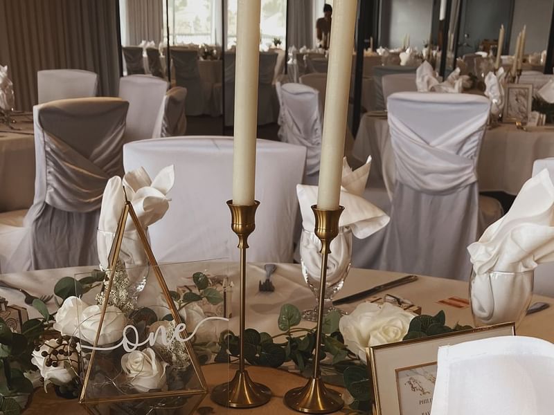 Table with candles, flowers, napkins, and glasses.