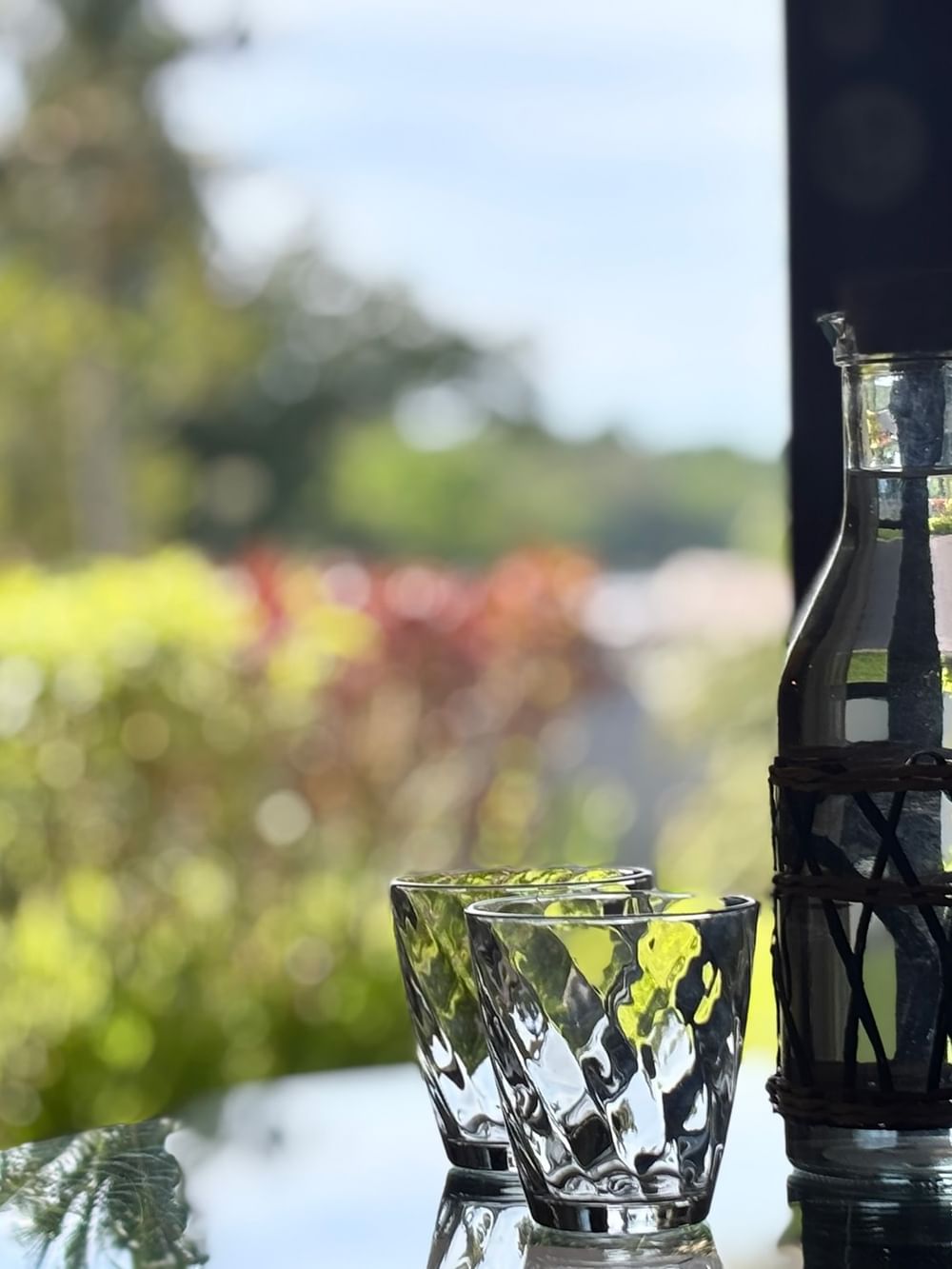 Glass carafe and cups on a table with garden view at Warwick Le Lagon Efate.