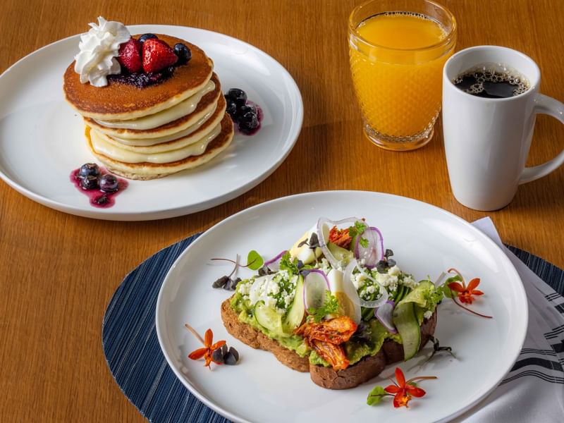 Palmea Kitchen breakfast with berry pancakes, shrimp avocado toast, orange juice, and coffee at The Diplomat Resort