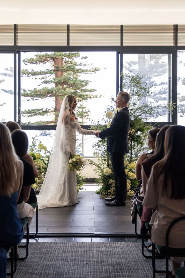 Wedding ceremony at Elysium Manly featuring a couple with floral decor under high ceilings, one of the best hotels in Manly