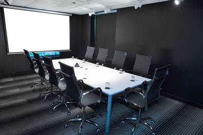 Black 2 Room with long table, comfy chairs and project screen at D Sabana Hotel