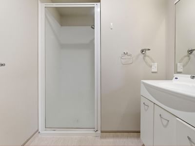 Modern bathroom with shower, sink, and white cabinets in UniLodge Stafford House.