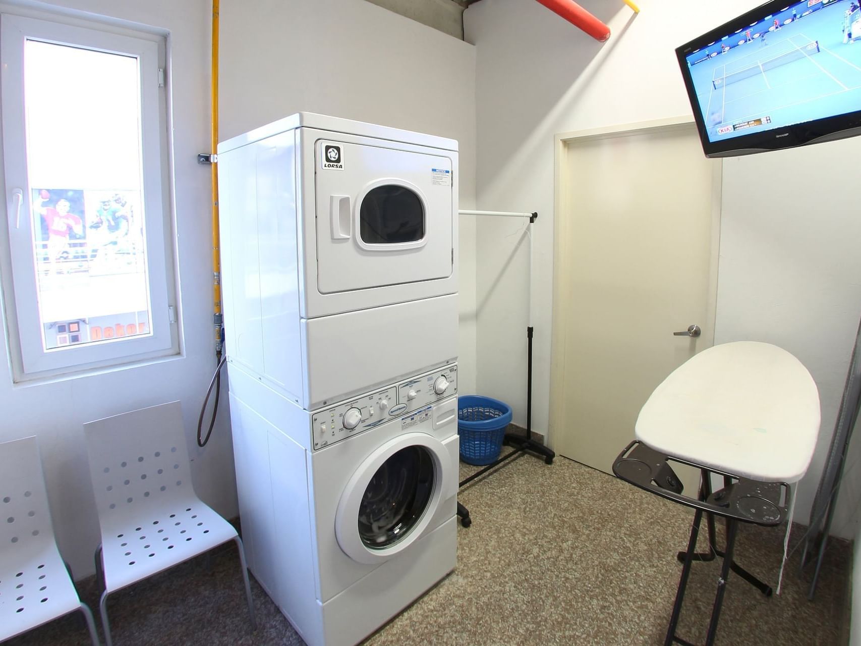 Washing machine, dryer, chairs & TV in Laundry Room, One Hotels