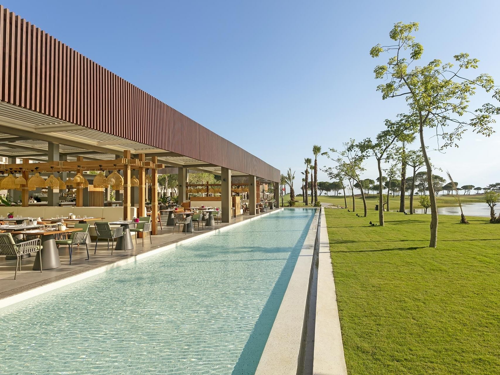 Dining area overlooking the pool & green landscape at Mare Main Restaurant in Cullinan Belek