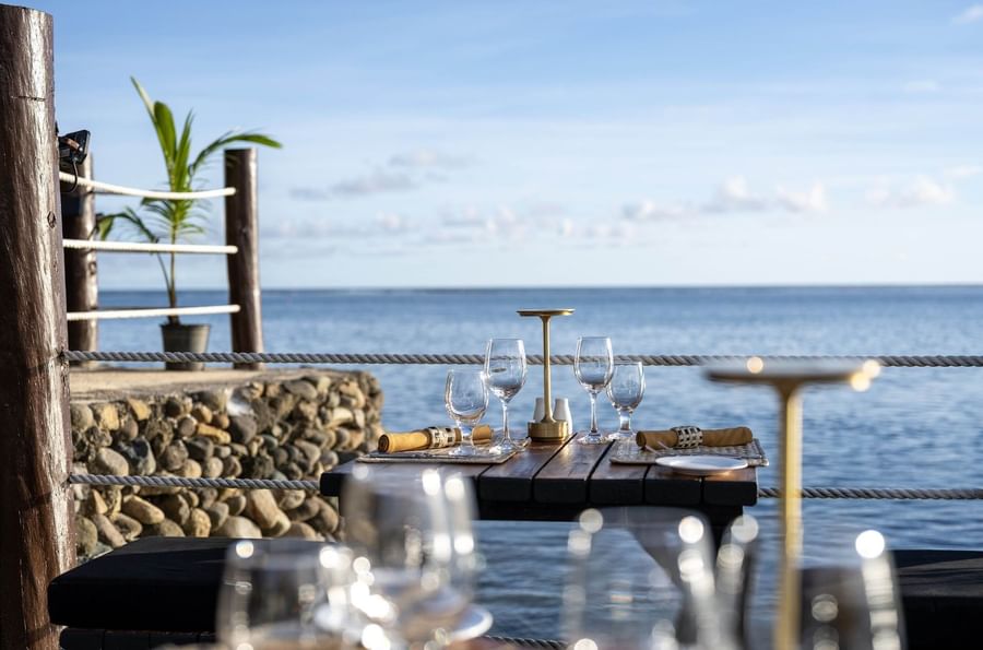 Dining table with wine glasses by a rope railing near the sea in Wicked Walu at Warwick Fiji Resort and Spa