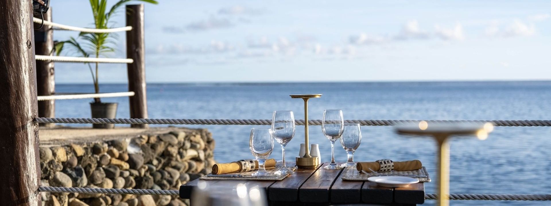 Dining table with wine glasses by a rope railing near the sea in Wicked Walu at Warwick Fiji Resort and Spa