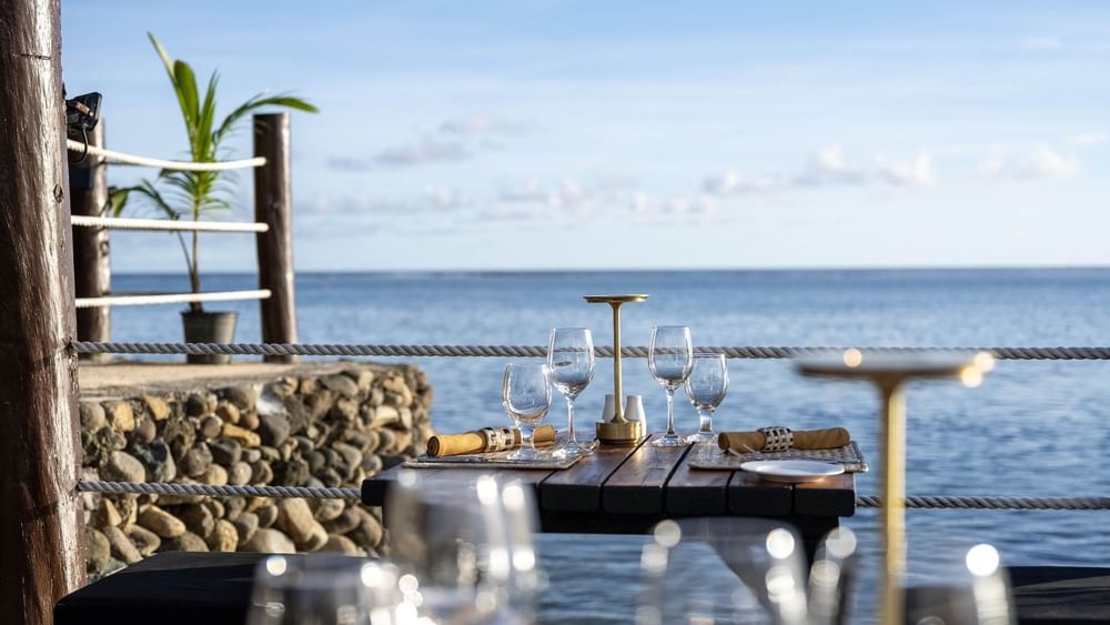 Dining table with wine glasses by a rope railing near the sea in Wicked Walu at Warwick Fiji Resort and Spa