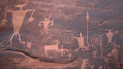 Ancient petroglyphs near Moab Valley Inn, depicting humanoid figures, animals, and spirals engraved on rocky surfaces