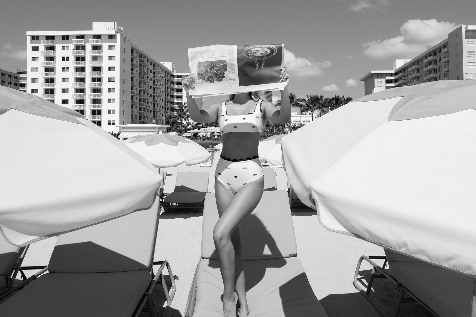 Woman reading a newspaper on a sunny beach with umbrellas at The Savoy Hotel & Beach Club
