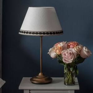 A lamp on a nightstand next to a vase of flowers in a bedroom at The Sparrow Hotel